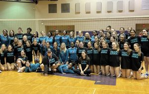 The Woodlawn High and St. Joseph's volleyball teams take a picture together in their coordinated black-and-teal shirts and jerseys in support of coach Maria Gonzalez.